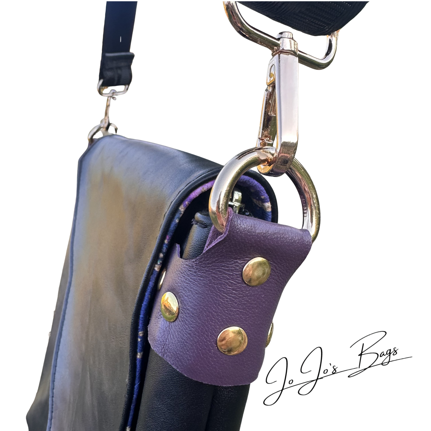 A close-up of a black leather shoulder bag with a purple leather strap cover featuring gold-tone studs and a gold-tone clasp, on a white background with the brand name 'Jo Jo's Bags' in script.