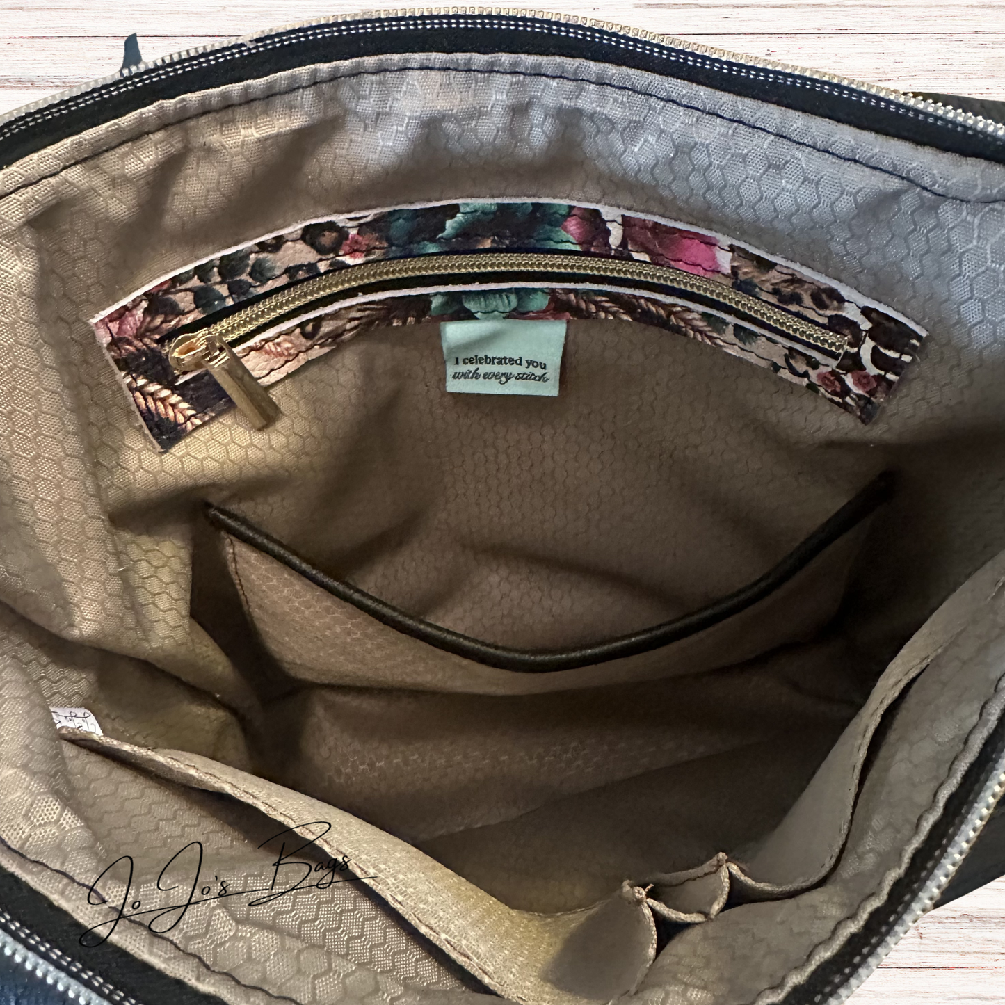 Close-up of the interior of a beige textured interior bag, showing a zippered pocket with a floral-patterned trim and a small fabric label.