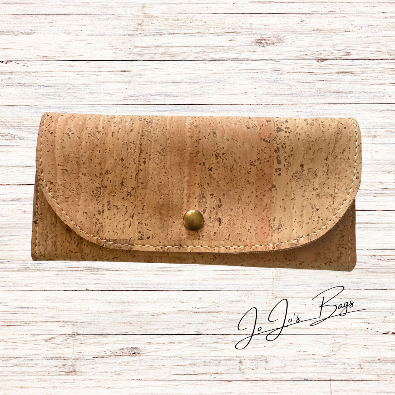 A tan cork wallet with a curved flap and a small brass snap button, displayed on a white wood plank background with a 'JoJo's Bags' logo in the bottom right corner.