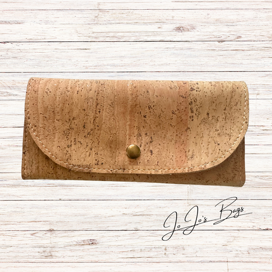A tan cork wallet with a curved flap and a small brass snap button, displayed on a white wood plank background with a 'JoJo's Bags' logo in the bottom right corner.