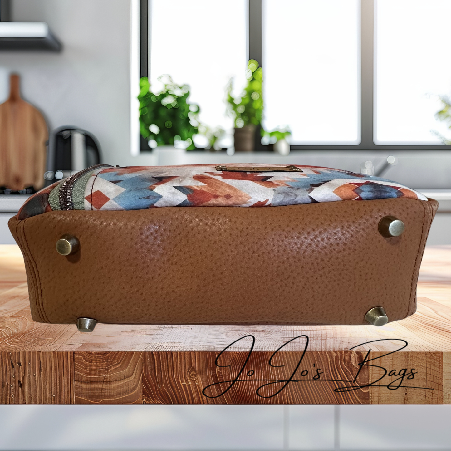 A brown textured bag with a colorful geometric patterned top, displayed on a wooden cutting board in a kitchen setting. The brand name 'Jo Jo's Bags' is written in script on the board.