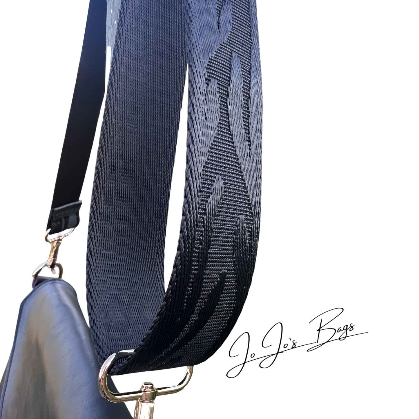 A close-up of a dark black shoulder bag strap with a textured, wavy pattern, attached to gold metal hardware and a black bag, on a white background. 