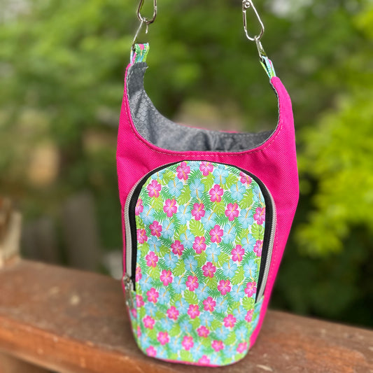 Pink pet carrier with floral pattern on a wooden surface with a blurred green background