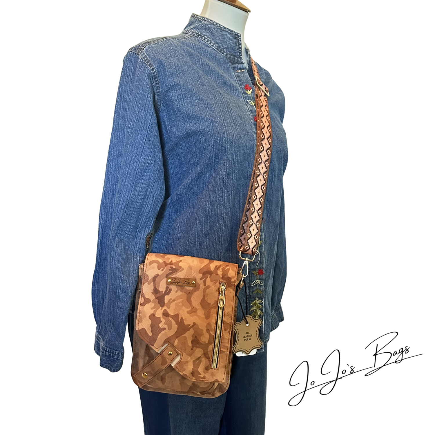 A tan and brown camouflage crossbody bag with a patterned strap, shown on a mannequin wearing a denim shirt and jeans. A 'JoJo's Bags' logo is visible in the bottom right corner.